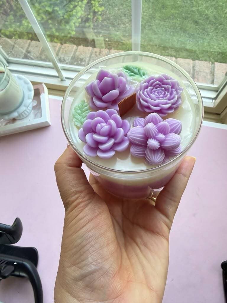 Vela lila de 14 oz coronada con suculentas y cactus de cera. Mecha de madera.
